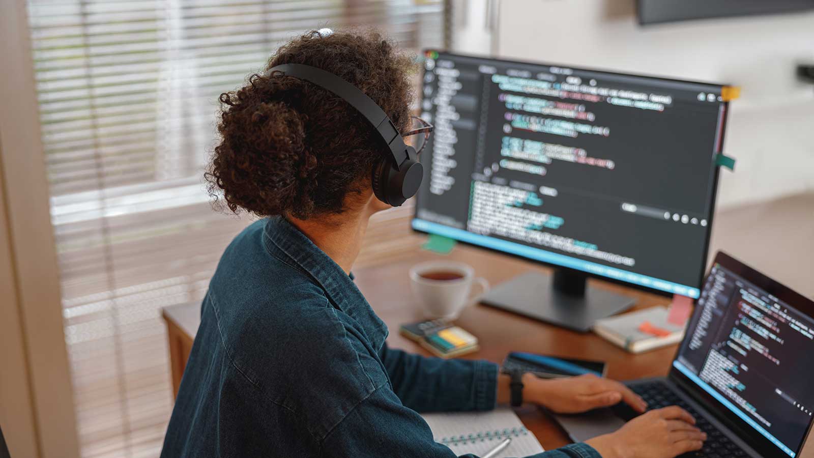 Person sitting at desk with monitors working on coding representing Computer Science program at Clarkson