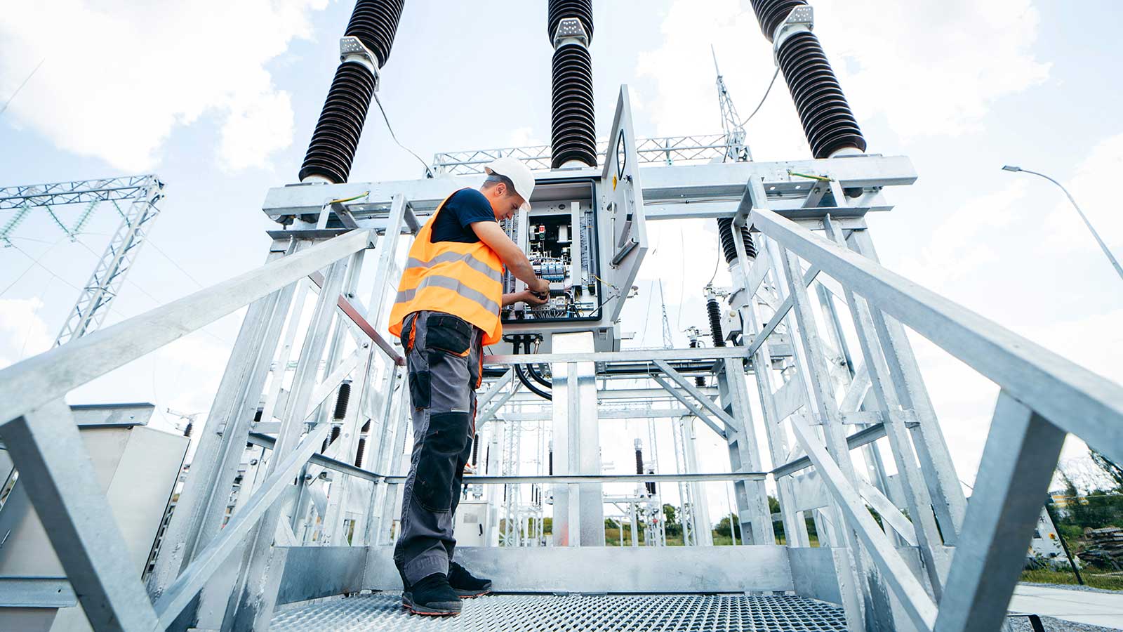 Worker with tools on electric tower representing Electrical-Engineering at Clarkson