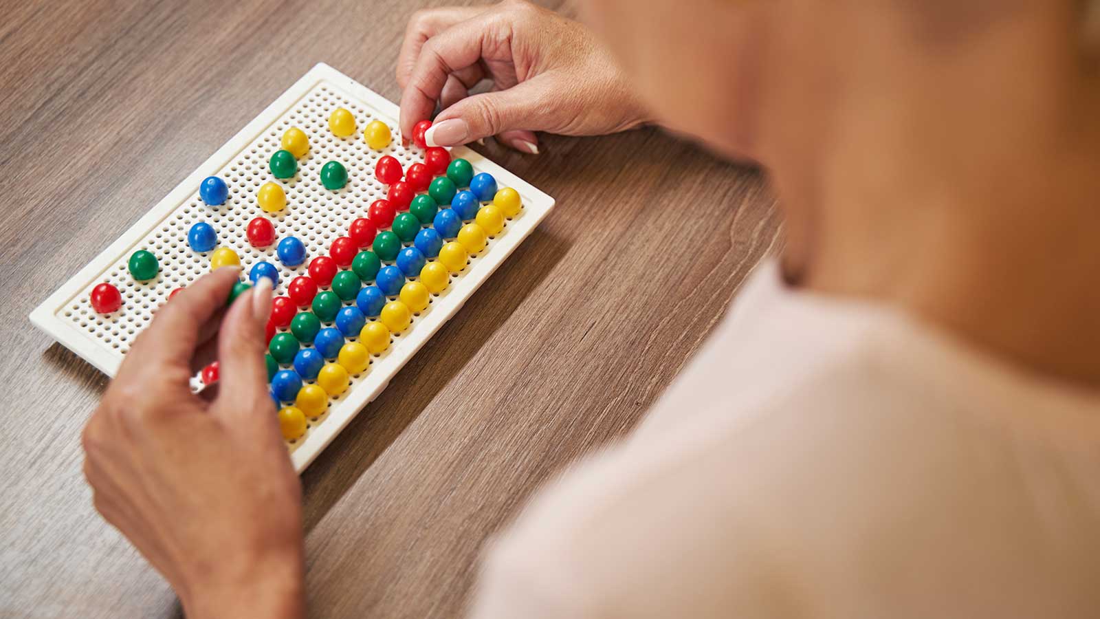 woman arranging colored pegs on a board representing occupational therapy program at Clarkson university 