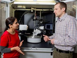 Professor and student standing in lab, discussing research.