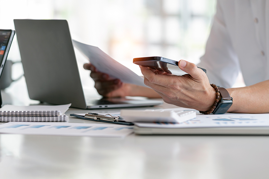 Person holding phone in front of computer