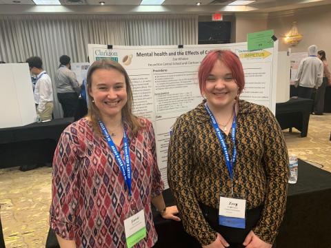 Zoe Whalen poses in front of her poster with her teacher