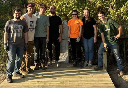 Group of seven students standing on a timber bridge deck constructed of pressure-treated lumber