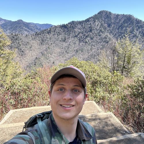 A photo of Justin Pettica on top of a mountain.