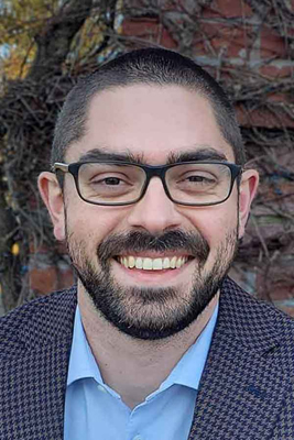 Close-up of Robert Thomas in a checkered sports jacket and a blue, open-collared shirt.